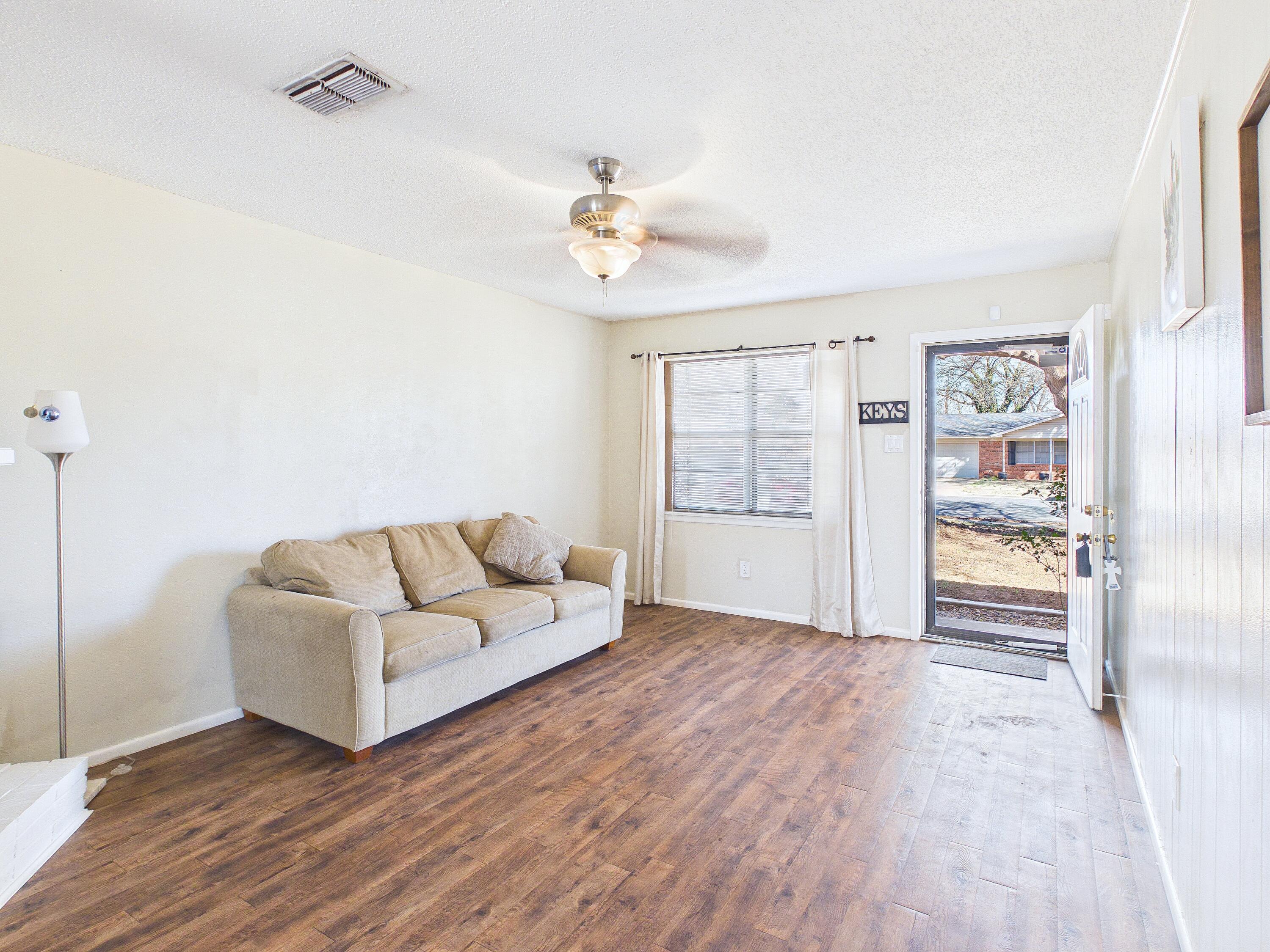 4825 10th Street Lubbock, TX 79416 - Photo 8 of 27 a living room with furniture and a chandelier