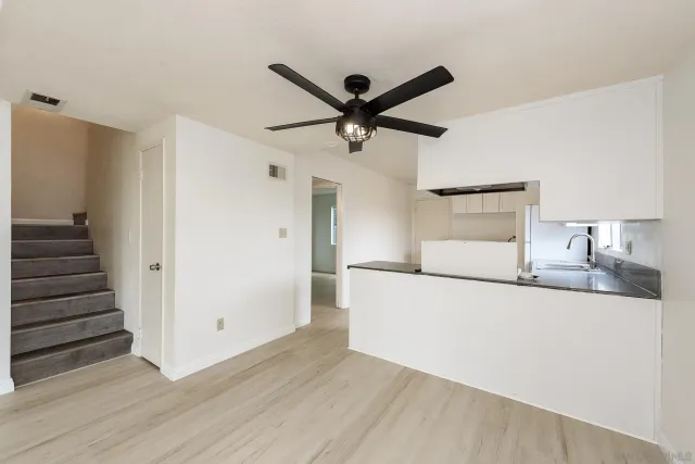 a kitchen view with wooden floor and a ceiling fan