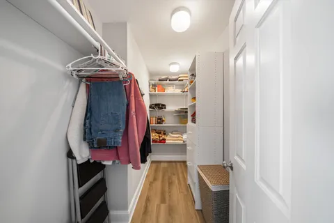 a view of walk in closet with clothes and shoes