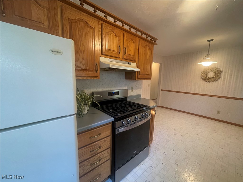 3707 River Road Vienna, WV 26105 - Photo 14 of 35 Kitchen with stainless steel gas stove, hanging light fixtures, and white refrigerator