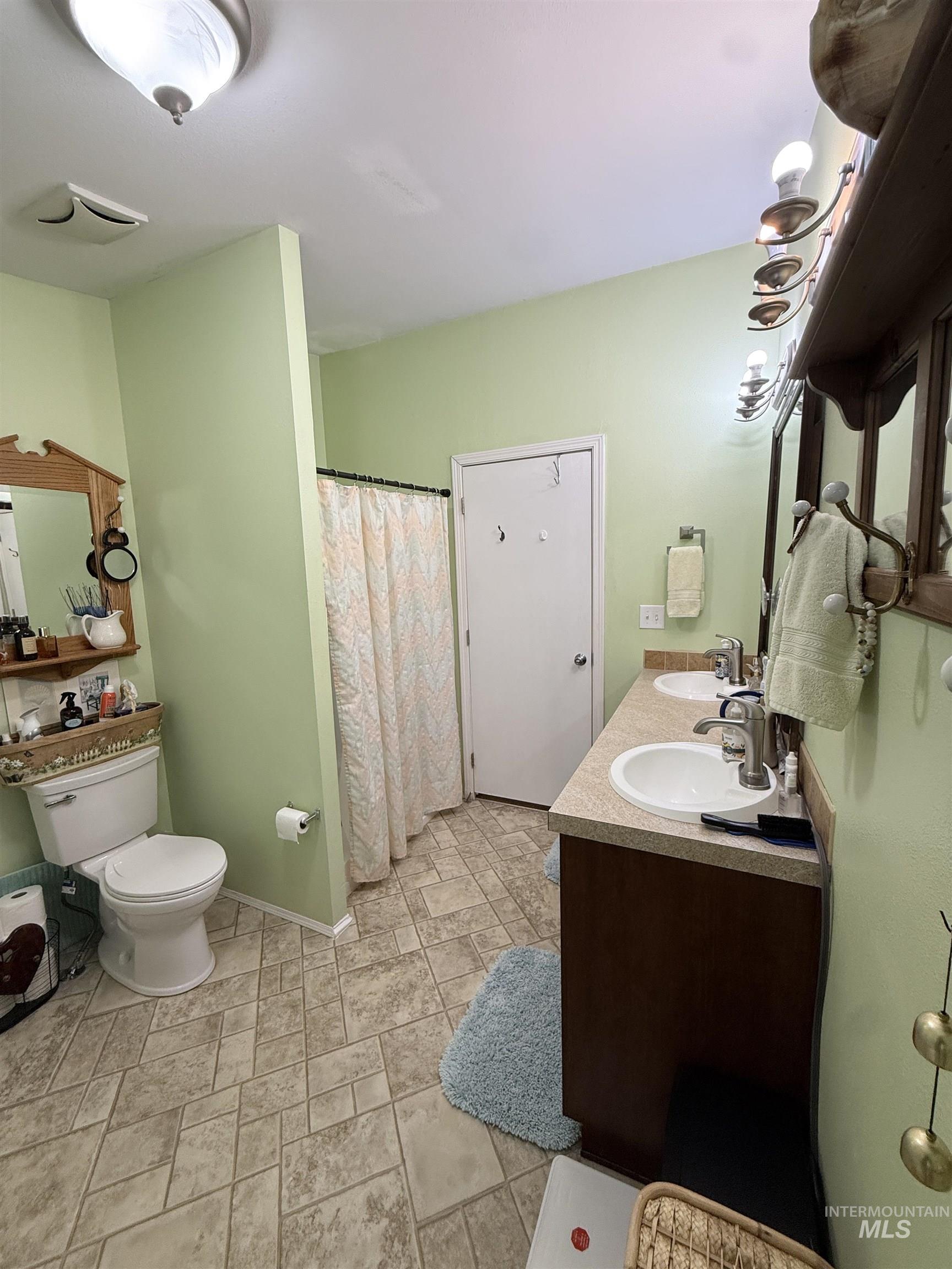 2750 Alden Road, Unit 12 12 Fruitland, ID 83619 - Photo 11 of 38 Bathroom with dual vanity, patterned shower curtain, and a ceiling-mounted light fixture