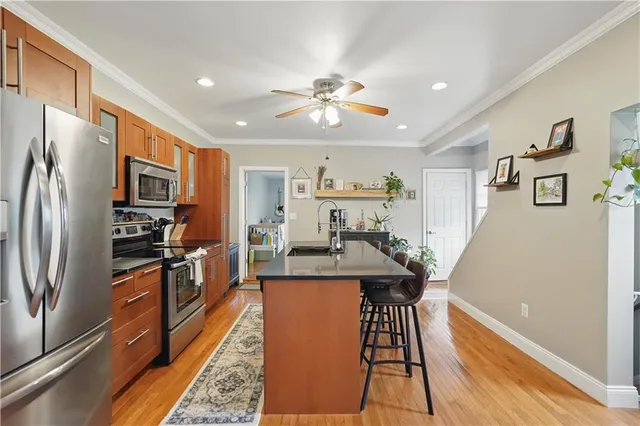 a kitchen with stainless steel appliances granite countertop a refrigerator a stove top oven a chimney cabinets and wooden floor