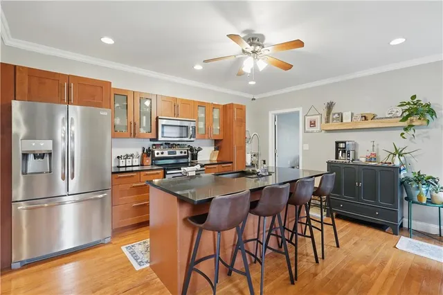 a kitchen with stainless steel appliances granite countertop a refrigerator a stove a sink a dining table and chairs with wooden floor