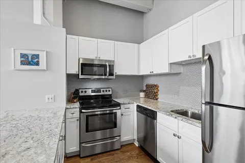 a kitchen with stainless steel appliances white cabinets and a stove top oven