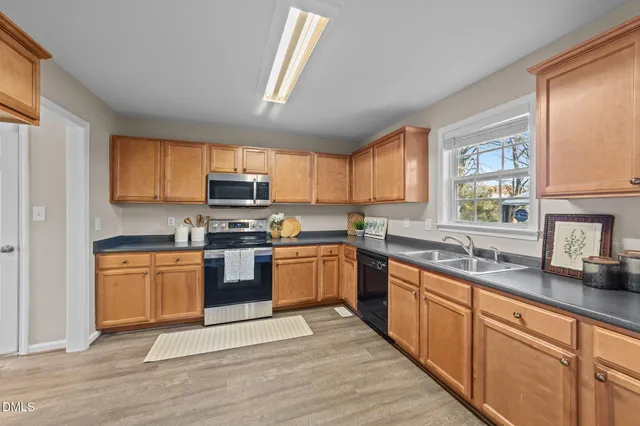 a kitchen with stainless steel appliances granite countertop wooden cabinets a stove a sink and a window
