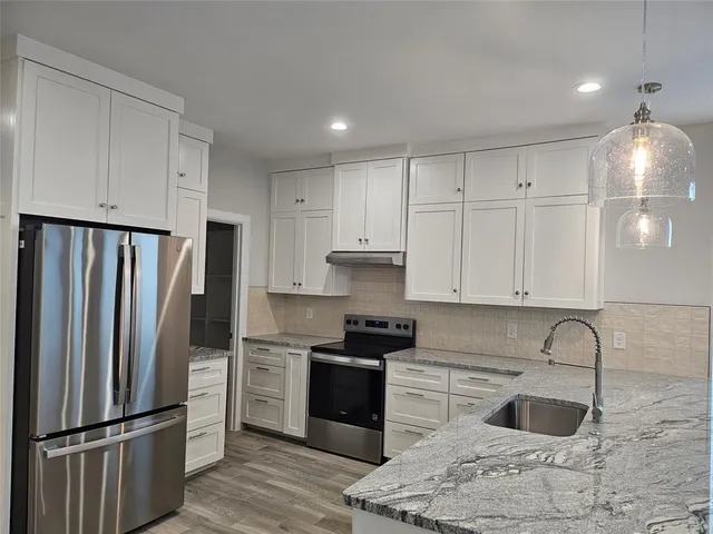a kitchen with granite countertop a refrigerator stove and sink
