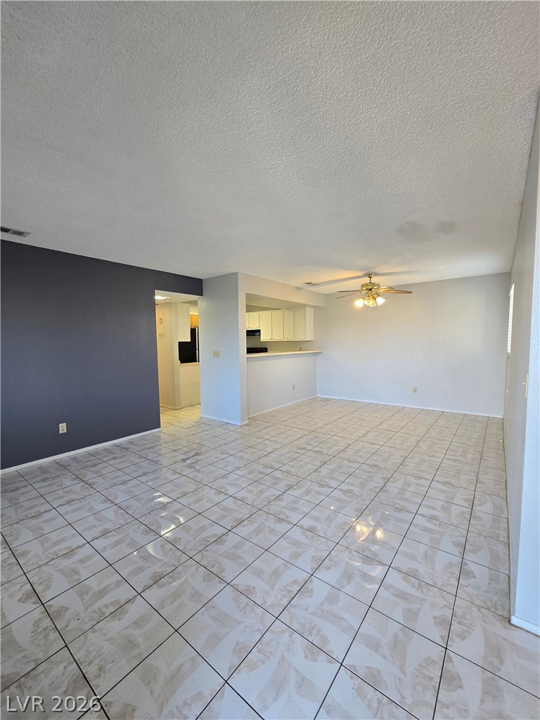 6750 Del Rey Avenue, Unit 133 Las Vegas, NV 89146 - Photo 4 of 34 A spacious living area featuring elegant tile flooring and an integrated kitchen pass-through.