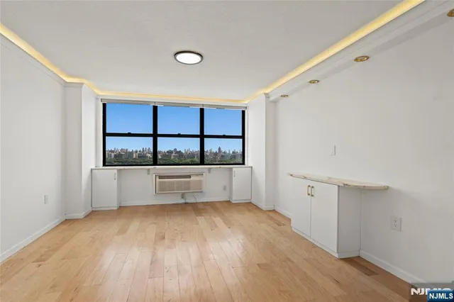 a view of an empty room with window and wooden floor