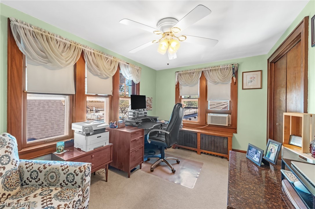 221 Raff Road Northwest Canton, OH 44708 - Photo 14 of 31 Room featuring multiple windows with wood trim, ceiling fan light fixture, carpeted flooring, and a built-in wood radiator cover