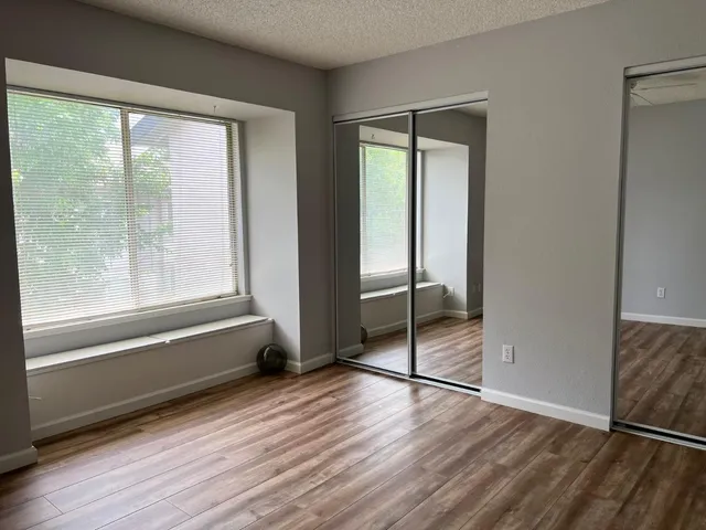 a view of empty room with wooden floor and fan