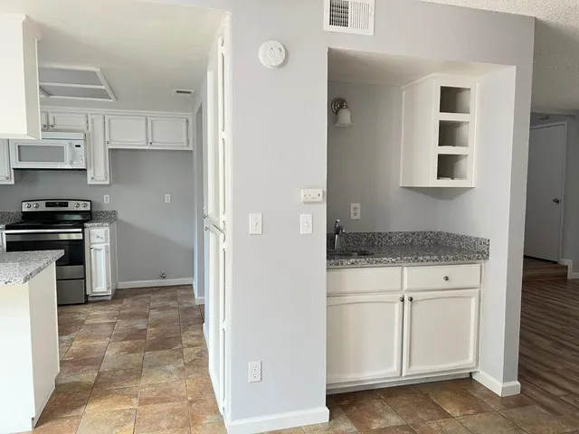 a kitchen with white cabinets and appliances