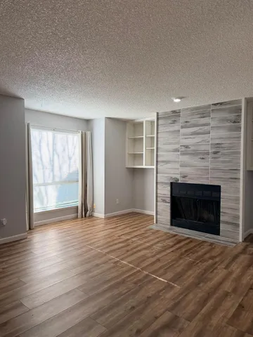 an empty room with wooden floor fireplace and windows