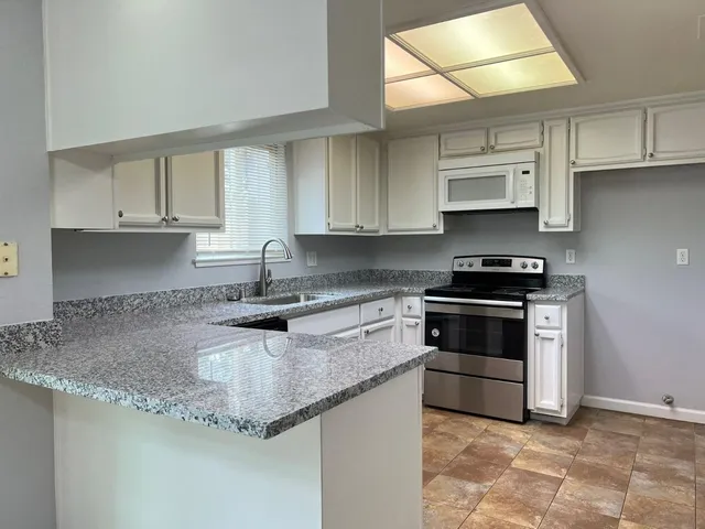 a kitchen with stainless steel appliances granite countertop a sink stove and cabinets
