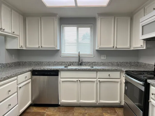 a kitchen with granite countertop white cabinets and a stove