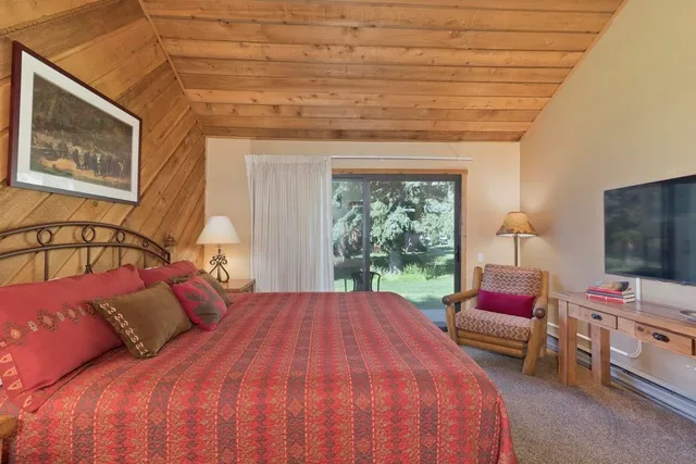 a bedroom with a bed a chair and a flat screen tv