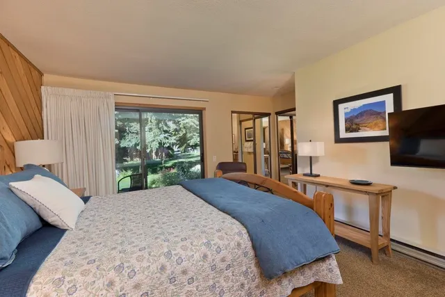 a spacious bedroom with a bed and a flat screen television