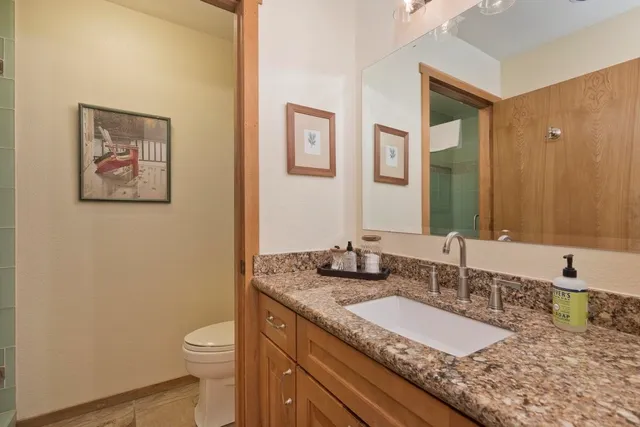 a bathroom with a granite countertop sink mirror vanity and toilet