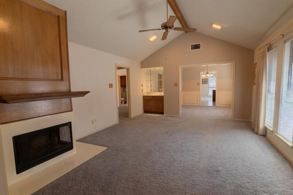 2028 Falcon Ridge Drive, Unit B Carrollton, TX 75010 - Photo 3 of 11 Unfurnished living room featuring ceiling fan, light carpet, a fireplace with flush hearth, a textured ceiling, and hanging lights