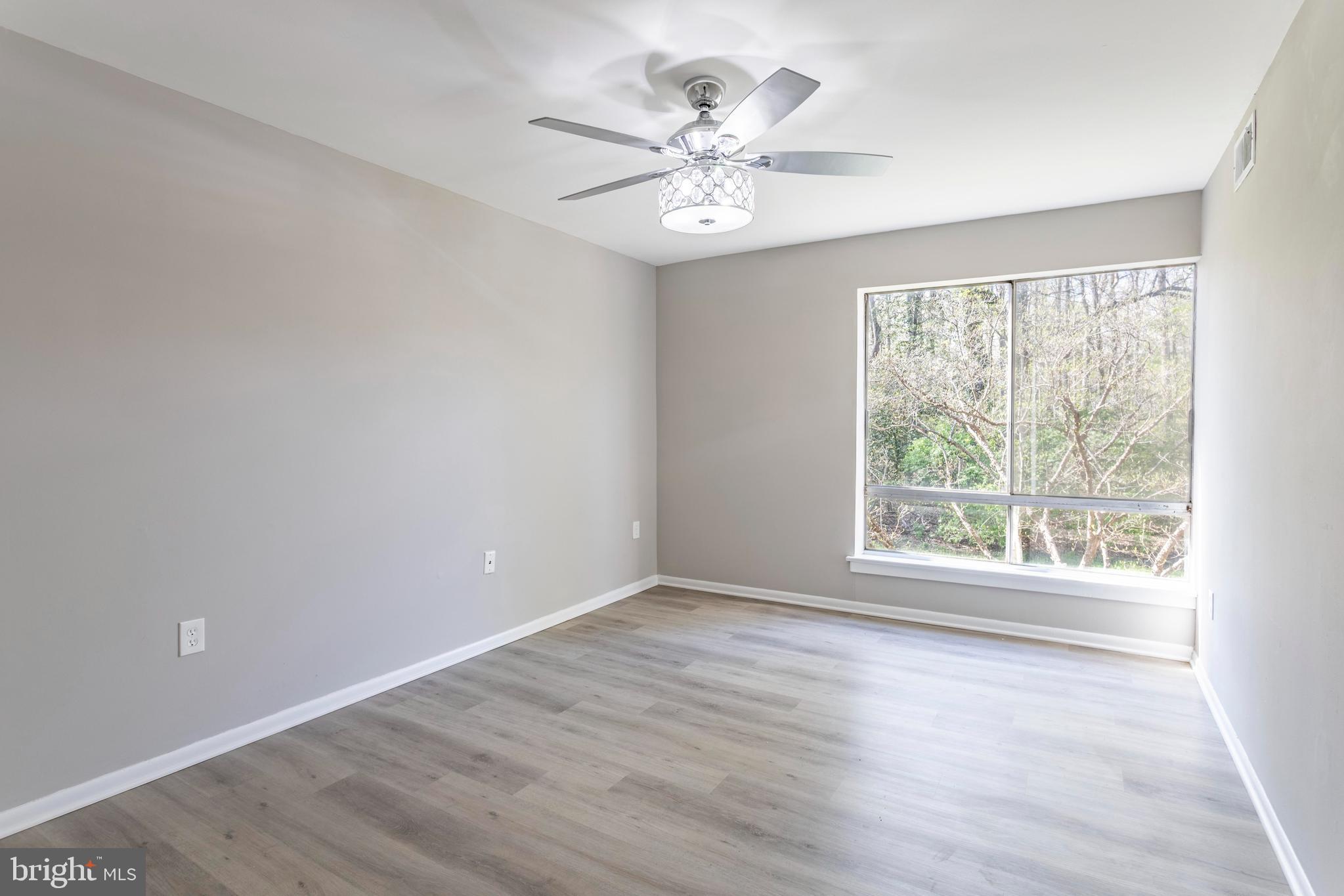 8467 Greenbelt Road, Unit 8467102 Greenbelt, MD 20770 - Photo 18 of 30 an empty room with wooden floor and windows