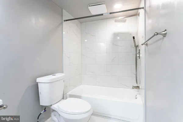 a white toilet sitting next to a bath tub and a shower