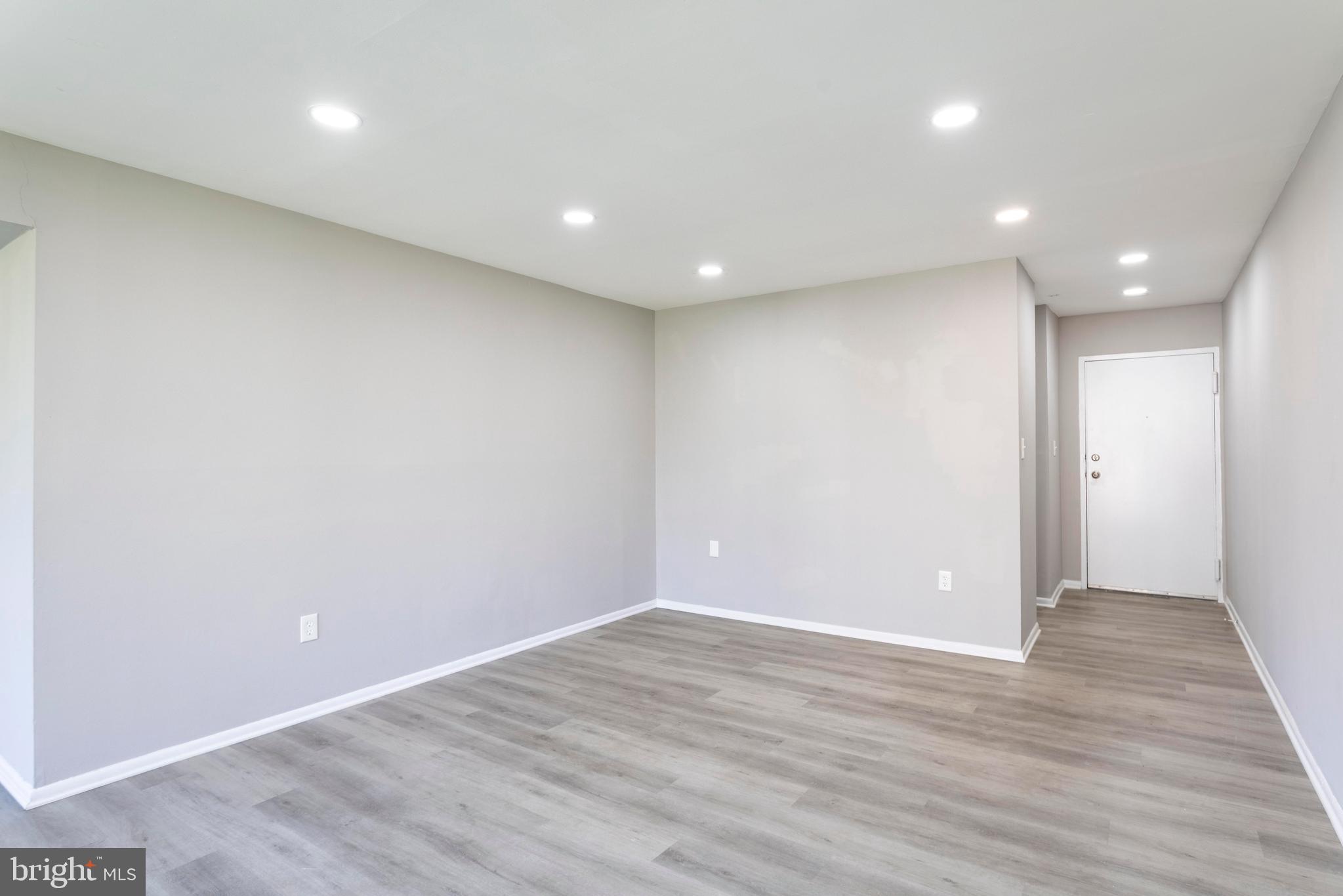 8467 Greenbelt Road, Unit 8467102 Greenbelt, MD 20770 - Photo 7 of 30 an empty room with wooden floor and entrance