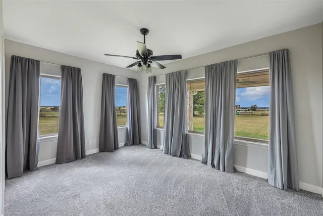 a view of a big room with windows and chandelier fan