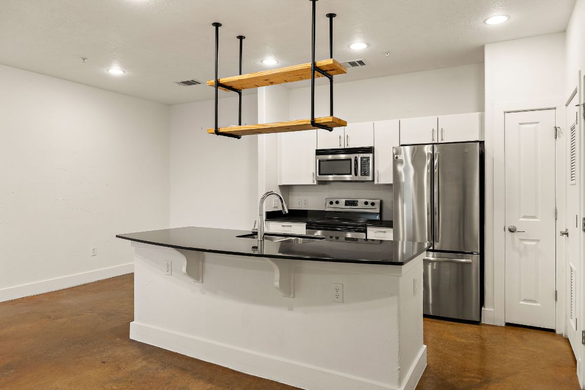 1807 Poquito Street, Unit 41 Austin, TX 78702 - Photo 10 of 23 a kitchen with kitchen island a counter space a sink appliances and cabinets