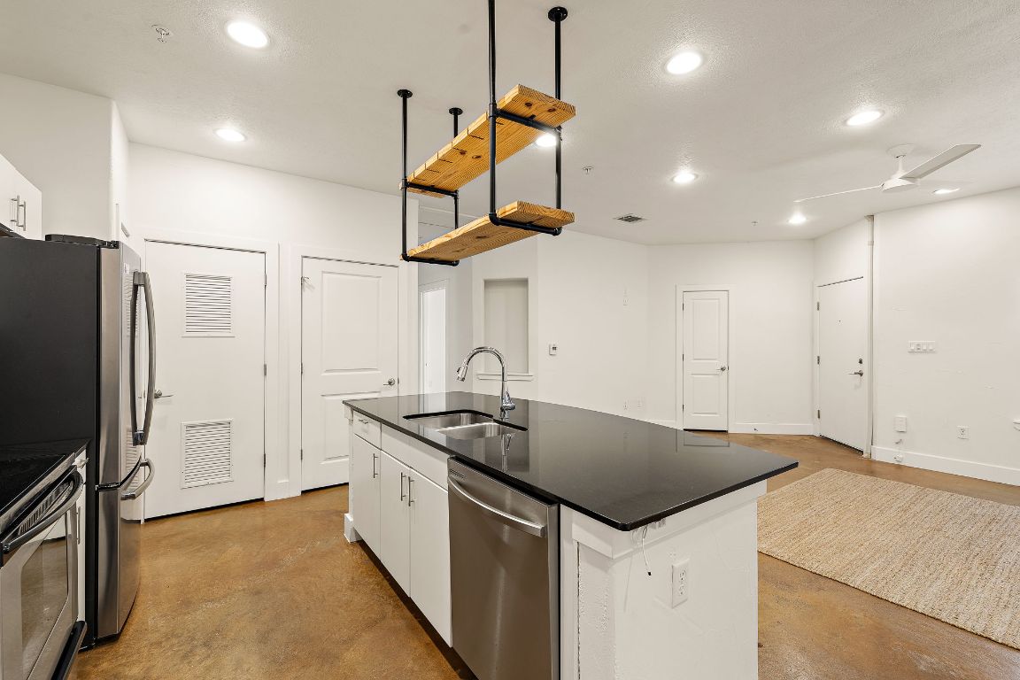 1807 Poquito Street, Unit 41 Austin, TX 78702 - Photo 13 of 23 a kitchen that has a sink a center island stainless steel appliances and cabinets