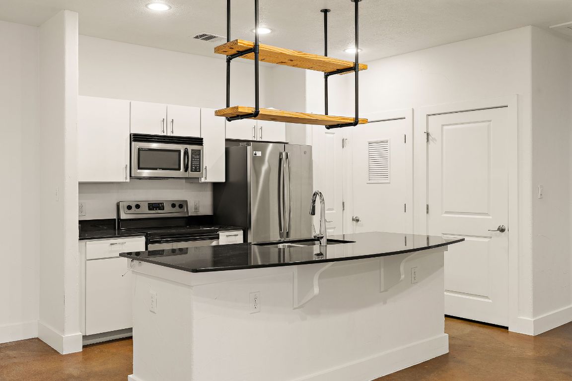 1807 Poquito Street, Unit 41 Austin, TX 78702 - Photo 8 of 23 a kitchen with stainless steel appliances a refrigerator a stove microwave and white cabinets