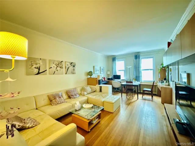 a living room with couches and kitchen view with wooden floor