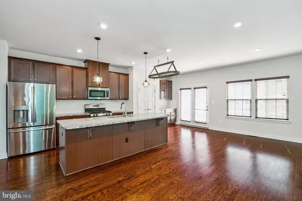a large kitchen with stainless steel appliances granite countertop a large counter top and wooden floors