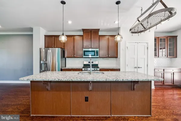 a kitchen with stainless steel appliances granite countertop a sink a refrigerator and wooden cabinets