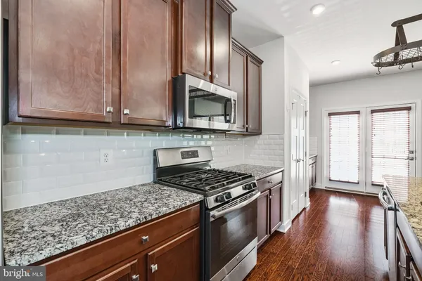 a kitchen with granite countertop wooden cabinets a stove and a wooden floor