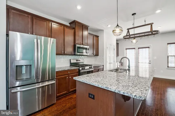 a kitchen with stainless steel appliances granite countertop a refrigerator a stove top oven a sink and dishwasher