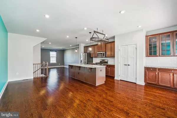 a large kitchen with hardwood floor and a view of living room