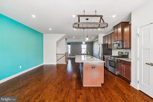 a kitchen with stainless steel appliances granite countertop a wooden floors a stove and a refrigerator