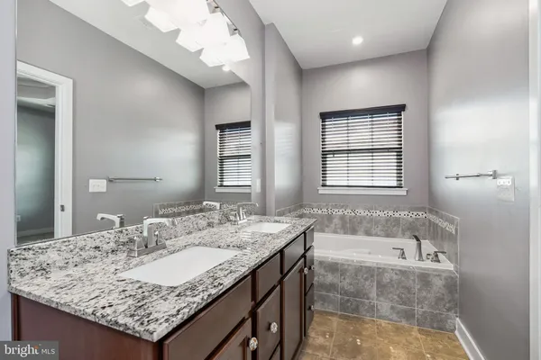 a bathroom with a granite countertop tub sink and mirror