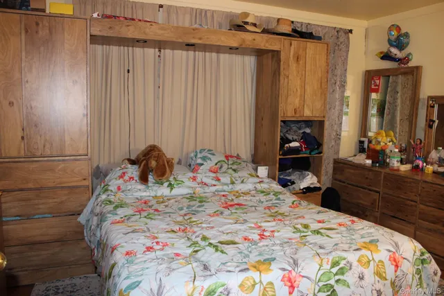 a bed sitting in a bedroom and dresser with mirror