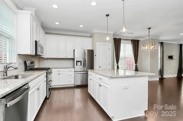 a kitchen with stainless steel appliances granite countertop a sink a stove a refrigerator and cabinets