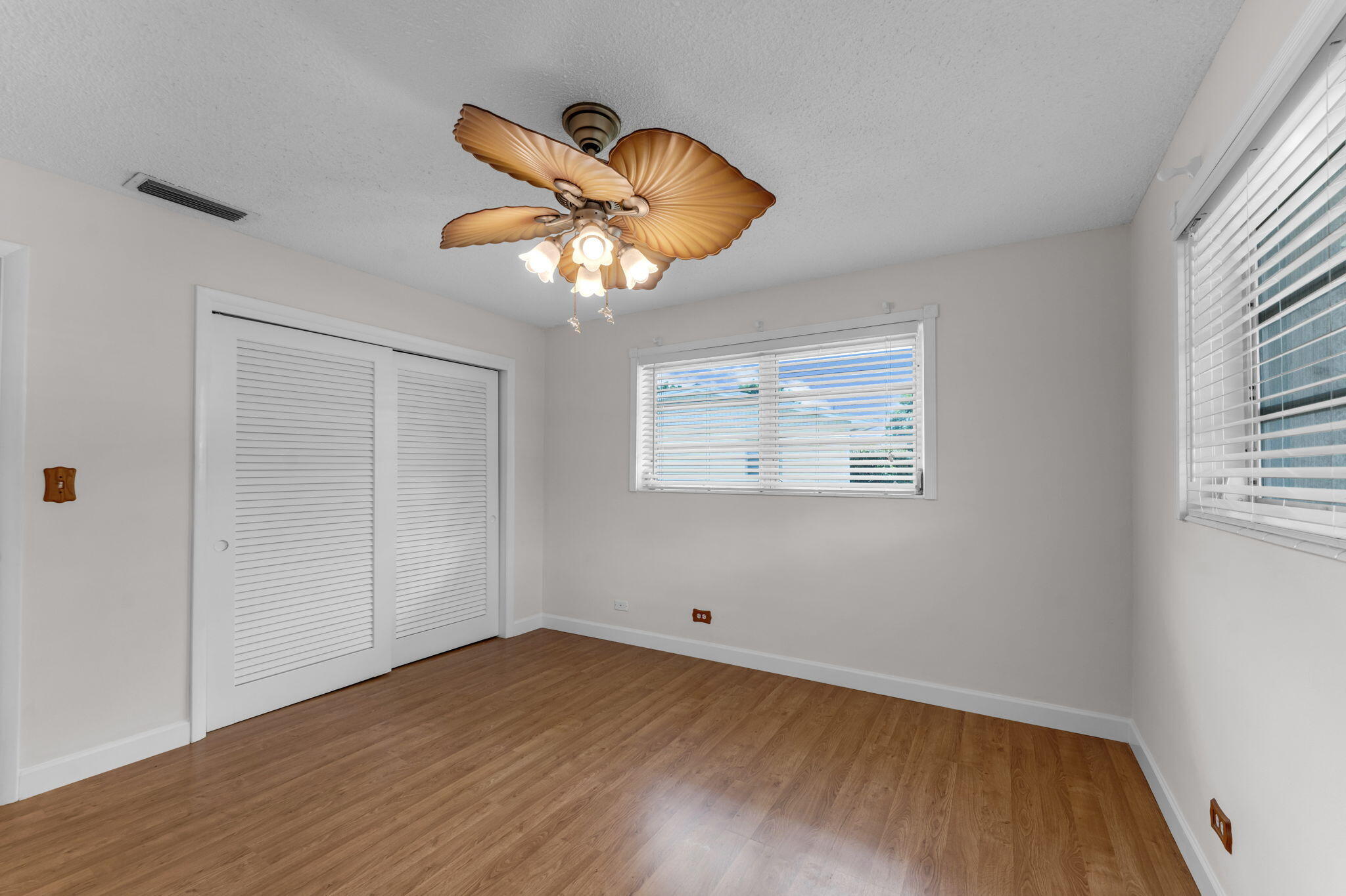 920 La Paloma Road Key Largo, FL 33037 - Photo 32 of 44 an empty room with wooden floor chandelier fan and windows