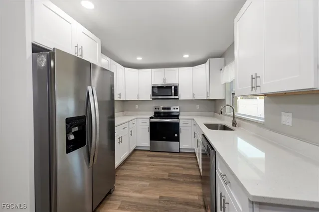 a view of kitchen with kitchen island wooden floor stainless steel appliances and cabinets