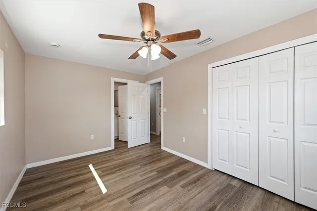 a view of an empty room with wooden floor and a ceiling fan