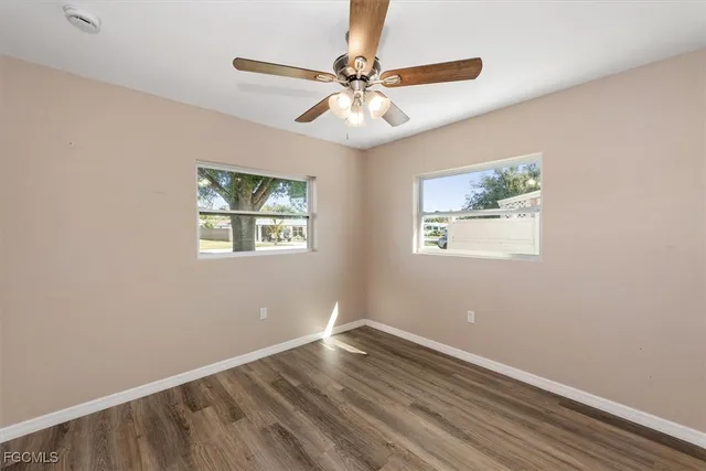 an empty room with wooden floor and fan