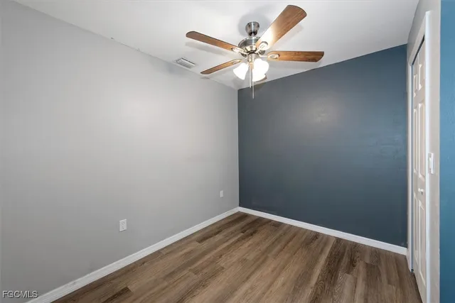 wooden floor in an empty room with a chandelier fan