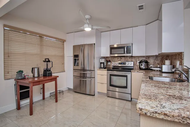 a kitchen with stainless steel appliances granite countertop a refrigerator stove top oven and sink
