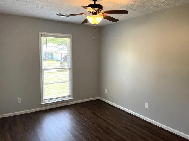 an empty room with windows and chandelier fan