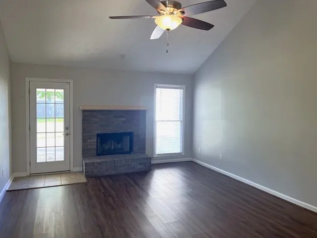 an empty room with wooden floor fireplace and windows