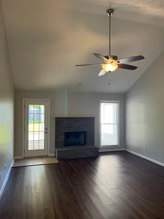 an empty room with windows a fireplace and wooden floor