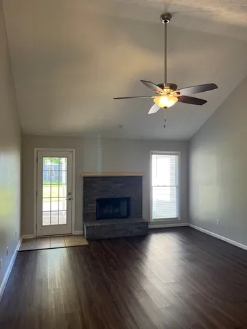 an empty room with windows a fireplace and wooden floor