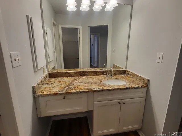a bathroom with a granite countertop sink and a mirror